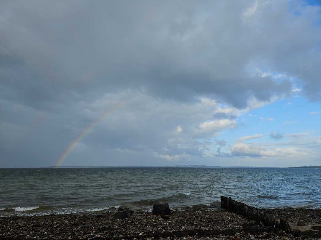 Ein Regenbogen in einer stürmischen Wolke über dem Meer