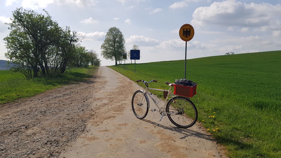 Mein Rad steht an der tscheschich/deutschen Grenze neben einem runden gelben Schild mit Bundesadler